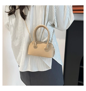 Mini apricot shell bag with lychee texture and gold chain worn with a striped shirt