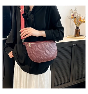 Close-up of wine red woven crescent bag with gold hardware and wide shoulder strap