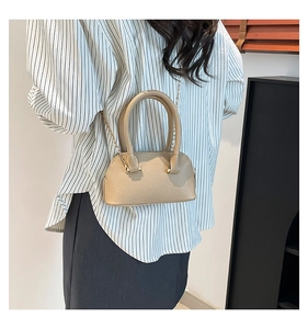 Mini beige pebble grain shell bag with gold chain strap shown on model during daily use