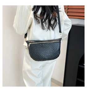 Detail of woven black leather chest bag featuring gold zipper and wide nylon strap
