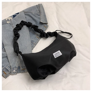 Detail of black nylon hobo bag with pleated cloud strap and fashion label on denim