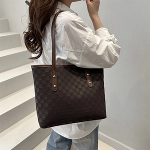 Deep brown quilted tote bag with golden rivets shown on model for stylish daily commute