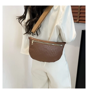 Detailed view of dark brown woven leather crossbody bag with wide strap on a model
