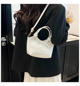 Detail of white litchi pattern leather tote bag with gold lettering and shoulder strap