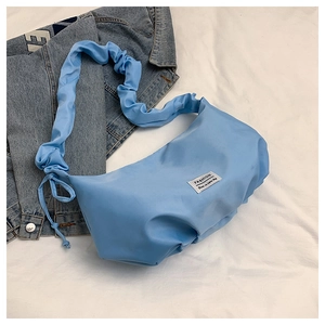 Detail of light blue nylon bag featuring ruffled shoulder strap and fashion label text