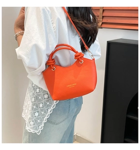 Detail of vibrant orange bucket bag with textured leather and knot handle detail