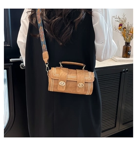 Detail of vintage cylindrical crossbody bag with ethnic jacquard strap and gold buckles
