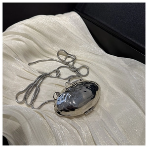 Close-up of a silver wavy mirror-finish mini purse with a sleek snake chain strap