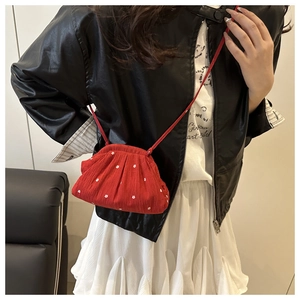 Close-up of a red floral crossbody bag with white polka dots and pleated drawstring top
