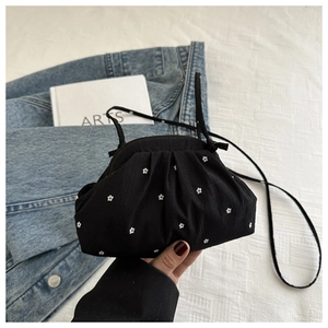 Macro detail of black floral shell bag with white polka dot prints and thin strap