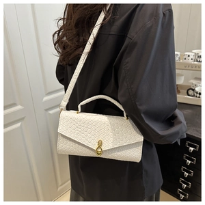 Detail of white woven crossbody bag with gold music note buckle on black shirt