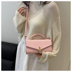 Detailed shot of pink woven shoulder bag featuring a unique gold musical note metal clasp