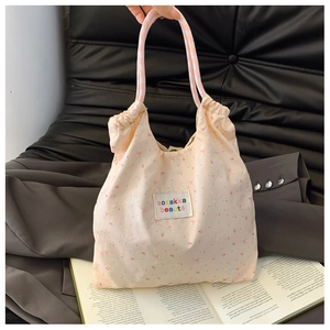 Détail du tote bag à fleurs avec motifs lapins roses, col froncé et anses à carreaux