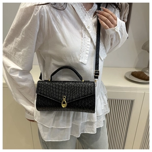 Detail of black woven texture handbag with golden infinity twist lock on the front flap