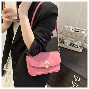 Pink leather shoulder bag with gold U-shaped lock shown on a black blazer outfit