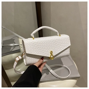 Close-up of white woven shoulder bag with a unique golden G-clef musical note metal clasp