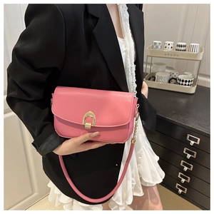 Detailed view of pink crossbody bag with gold horseshoe buckle worn on model