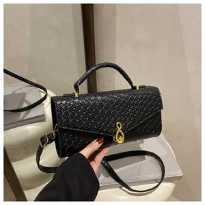 Close-up of black woven leather handbag featuring a signature gold infinity metal buckle