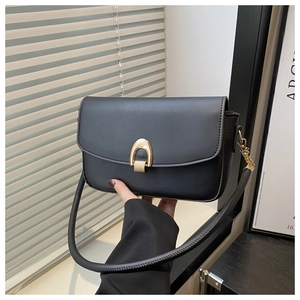 Close-up of black matte leather shoulder bag with a gold horseshoe buckle detail