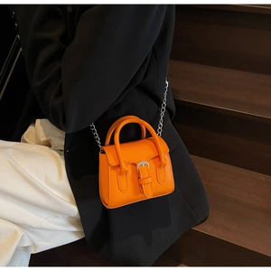 Close-up of orange leather mini square bag with lychee texture and silver buckle