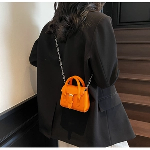 Detail of bright orange mini square bag with silver chain strap and top handle