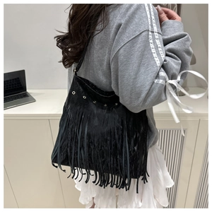 Detail of black suede hobo bag with long tassels and gold metal ring embellishments