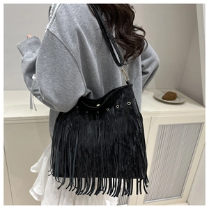 Detailed close-up of a black fringed shoulder bag featuring metallic gold eyelets and straps