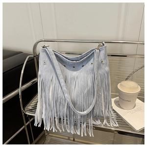 Détail du sac à bandoulière à franges bleu clair grisâtre sur une étagère minimaliste