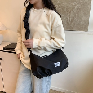Minimalist black pleated strap crossbody bag with fashion label and nylon texture