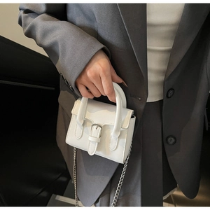 Mini white PU handbag with silver buckle and metal chain strap held by a model
