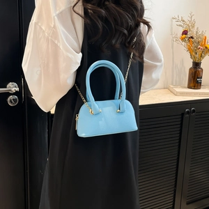 Mini light blue leather shell handbag with gold chain strap shown on a female model