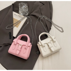Detailed close-up of pink and white mini handbags with leather buckles and silver chains