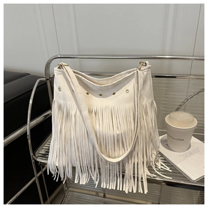 Détail du sac à bandoulière blanc à franges avec œillets sur étagère moderne