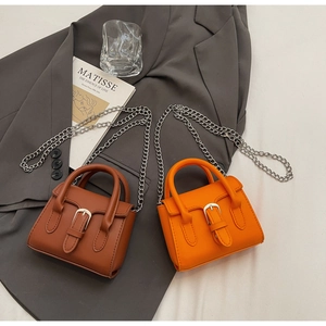 Detail of mini trapezoid crossbody bags in brown and orange with silver chain straps