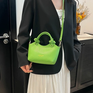 Vibrant green textured leather bucket bag with gold accents and knotted top handle