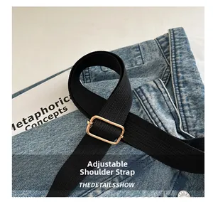 Detail of adjustable black nylon shoulder strap with gold metal buckle on blue denim