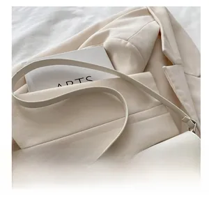 Detailed top view of minimalist cream leather baguette bag with metal rings and shoulder strap