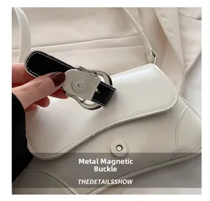 Detailed view of the magnetic silver buckle on the creamy white PU leather shoulder bag