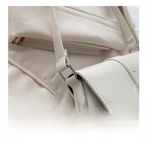 Close-up of metal ring buckle and fine leather texture on a white shoulder bag
