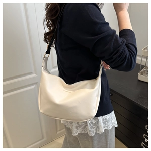 Side view of cream hobo shoulder bag with adjustable strap and gold logo lettering