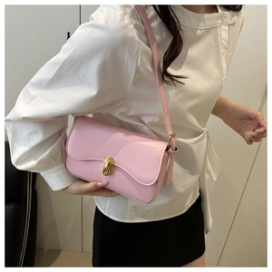 Detail of a pink leather shoulder bag with a gold cylindrical rotating lock on the flap