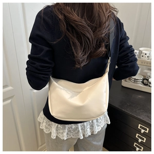 Détail du sac à main blanc cassé avec bandoulière tissée large porté par le mannequin