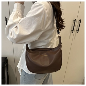 Close-up of brown semi-circle PU leather bag with gold buckle and adjustable strap