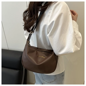 Detail of brown soft PU tote bag featuring adjustable black fabric shoulder strap and gold buckle