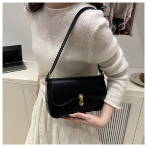 Detail of a black leather rectangular shoulder bag with golden metallic twist lock buckle