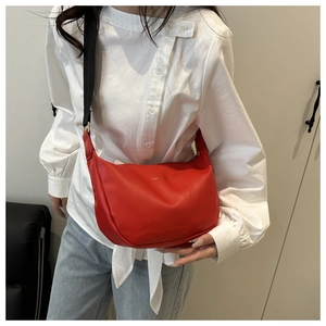 Détail du sac croissant rouge avec large bandoulière et texte doré embossé fashion