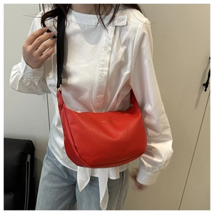 Detailed view of a red crescent Hobo bag with adjustable black strap on a model