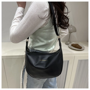 Close-up of black leather crescent bag with adjustable nylon strap and gold lettering