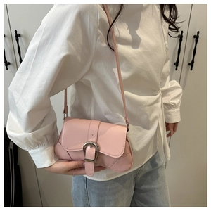Detail view of a pink leather saddle bag with silver buckle and crossbody shoulder strap