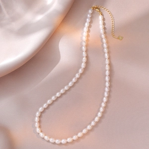 Macro detail of natural freshwater pearls with S925 silver heart tag on gold chain
